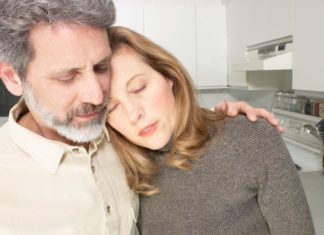 A man holds a woman. She looks unwell.