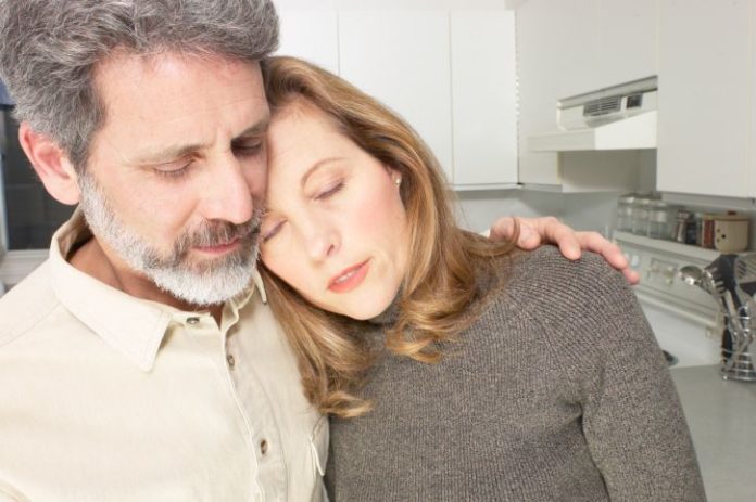 A man holds a woman. She looks unwell.