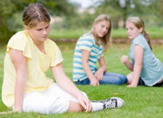 Two young girls bullying other young girl outdoors