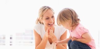 Mother and daughter indoors playing and smiling