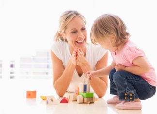 Mother and daughter indoors playing and smiling