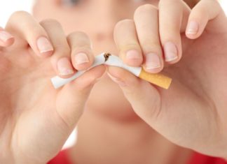 Young woman breaking a cigarette in half.