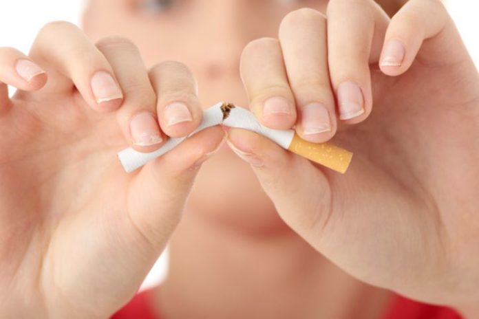 Young woman breaking a cigarette in half.