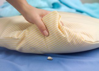 Woman's hand lifting a pillow showing a tooth waiting for the tooth fairy