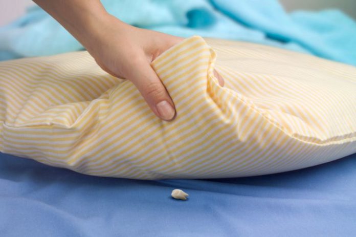 Woman's hand lifting a pillow showing a tooth waiting for the tooth fairy