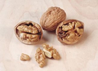 A cluster of walnuts, two cracked open, one whole.