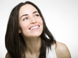 A woman with dark hair and perfect teeth smiles.