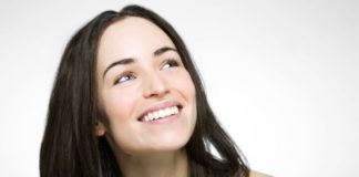 A woman with dark hair and perfect teeth smiles.