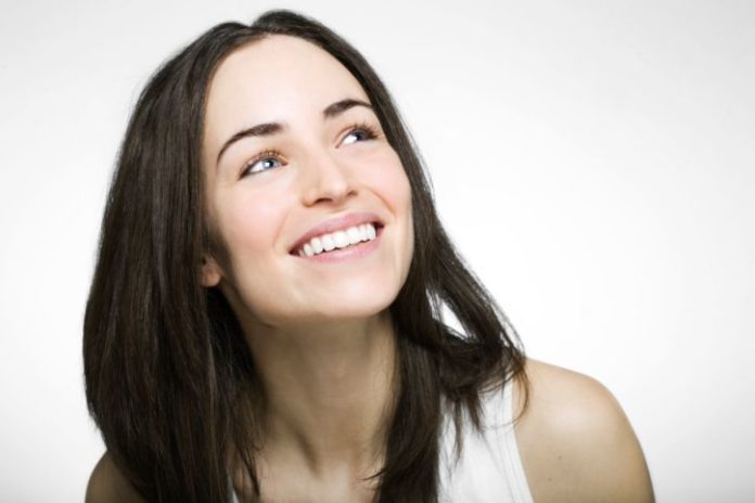 A woman with dark hair and perfect teeth smiles.