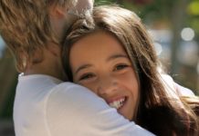 A teenage couple hug. The girl's face is to camera.