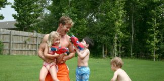 Boys and girl play with dad in the kiddie pool