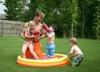 Boys and girl play with dad in the kiddie pool