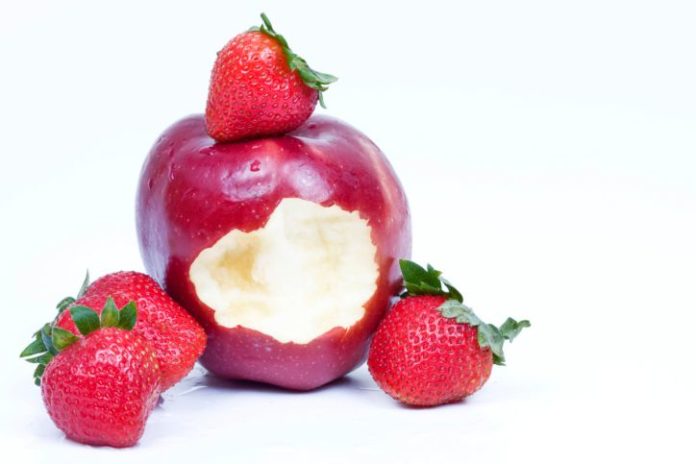 Fresh strawberries with a bitten wet red apple.