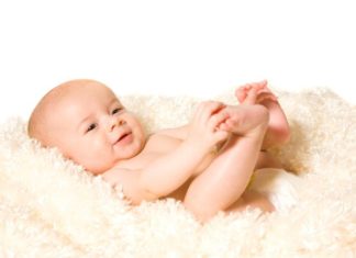 Baby on fluffy cream colored blanket.