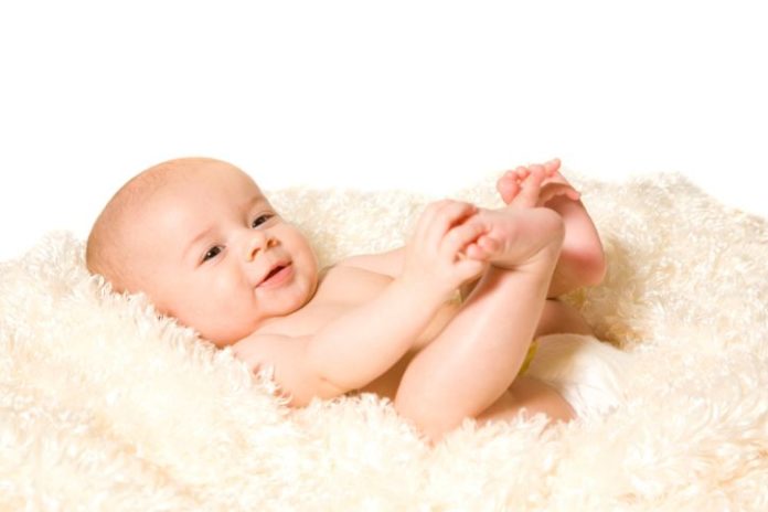 Baby on fluffy cream colored blanket.