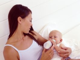 Woman feeding hungry baby with bottle.