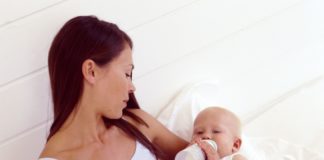 Woman feeding hungry baby with bottle.