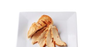 Cooked chicken breast, sliced and fanned on a white plate.