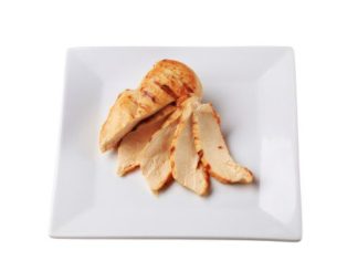 Cooked chicken breast, sliced and fanned on a white plate.