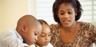 Mother watching children coloring in book with crayons