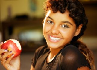 Beautiful smiling girl eating an apple.