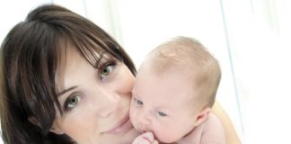 Close up shot of dark haired woman with small baby.