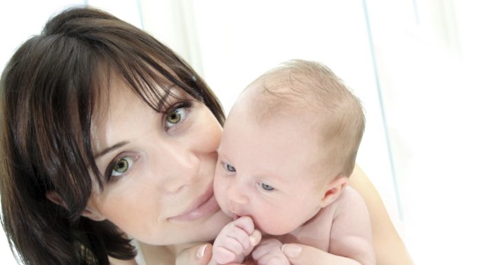 Close up shot of dark haired woman with small baby.
