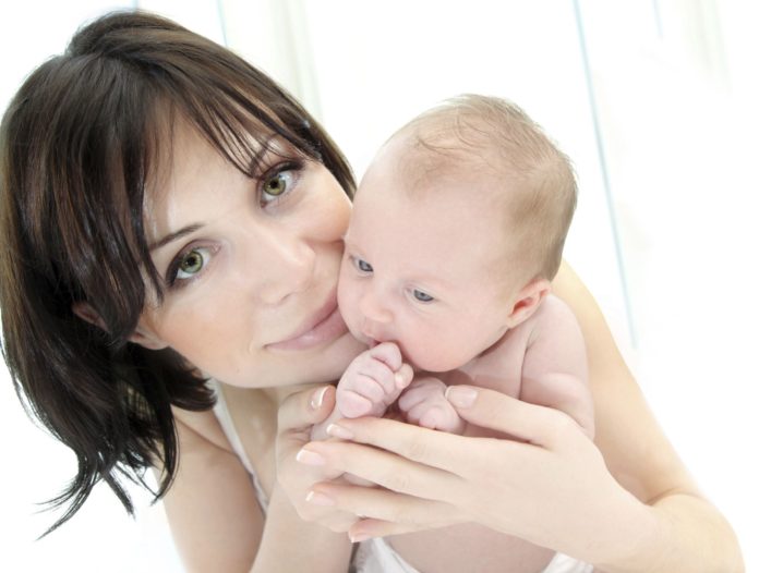 Close up shot of dark haired woman with small baby.