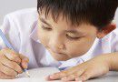 Male Student Working At Desk In Chinese School Classroom