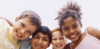 Happy children of different ethnicities smile to camera.