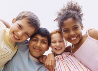 Happy children of different ethnicities smile to camera.