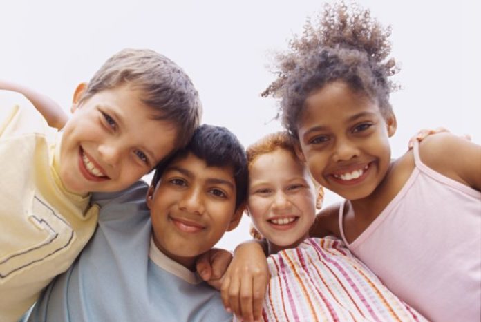 Happy children of different ethnicities smile to camera.