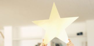 Boy holding a gold star above his head.