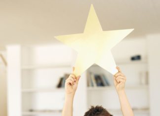 Boy holding a gold star above his head.