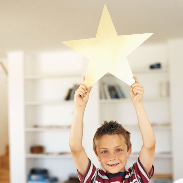 Boy holding a gold star above his head.
