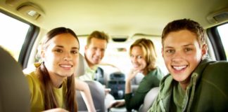 Portrait of a teenage boy and girl (17-20) with parents in a car.