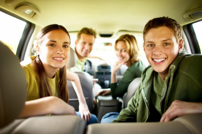 Portrait of a teenage boy and girl (17-20) with parents in a car.